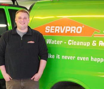 Male SERVPRO employee standing in front of SERVPRO poster and office supplies