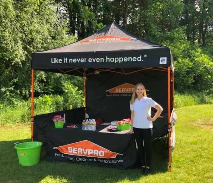 SERVPRO employee standing in front of company tent display on a sunny summer day.