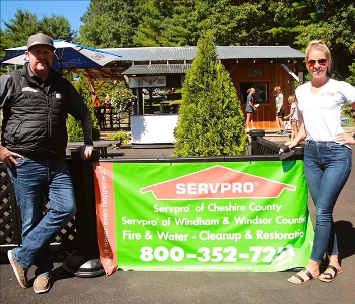 Two persons standing next to a business sign at a local mini golf course.