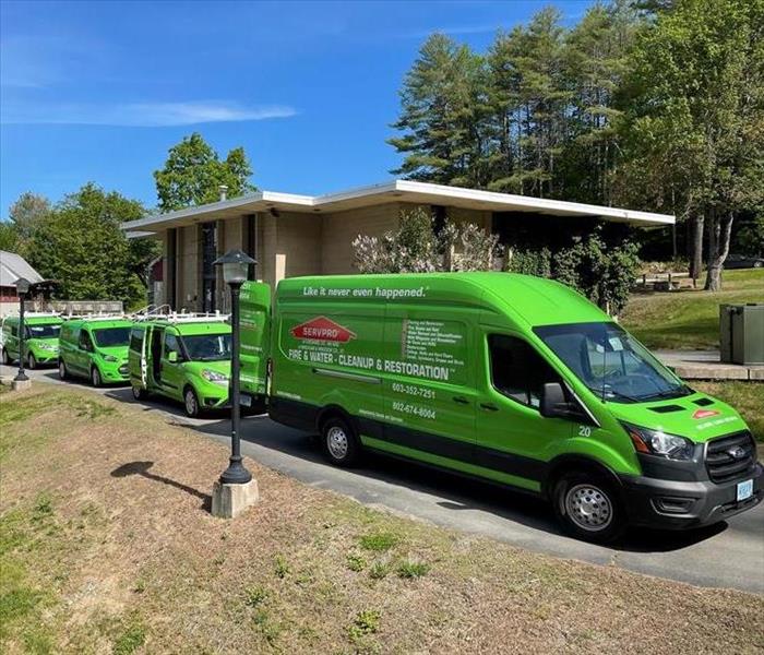 Row of green SERVPRO trucks outside of commercial property.