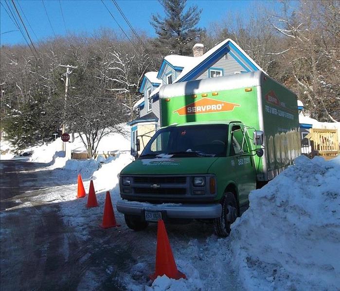 SERVPRO truck parked at a residence surrounded by tall banks of snow.