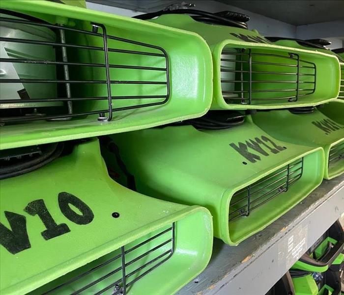 Several bright green air movers stored on a shelf.