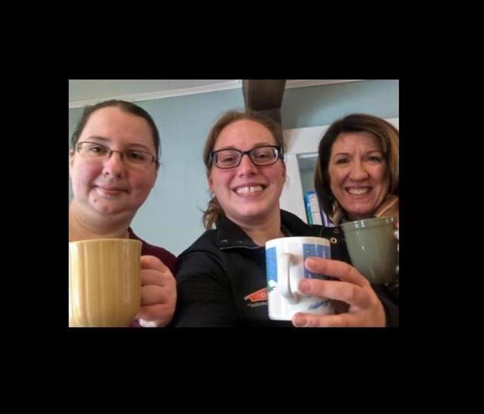 three ladies smiling while holding coffee mugs