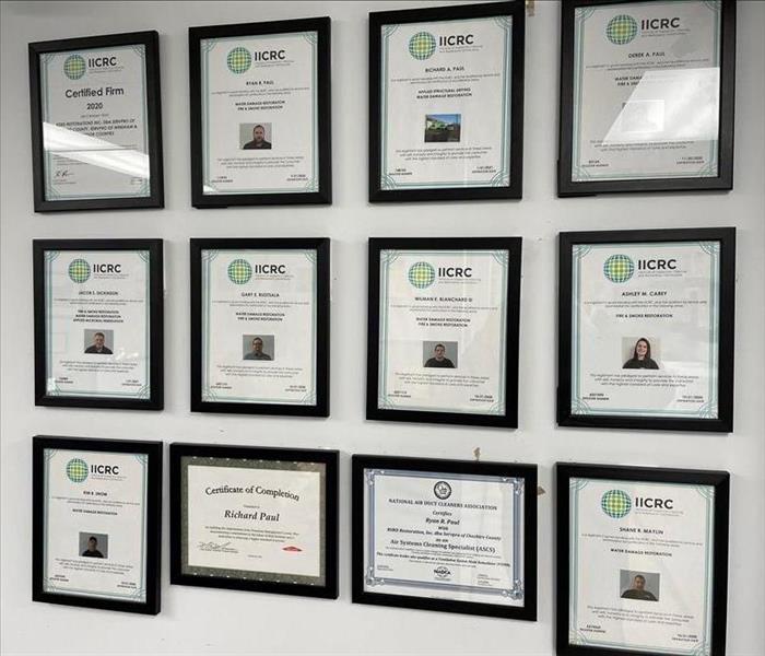 Framed certificates on a white office wall.