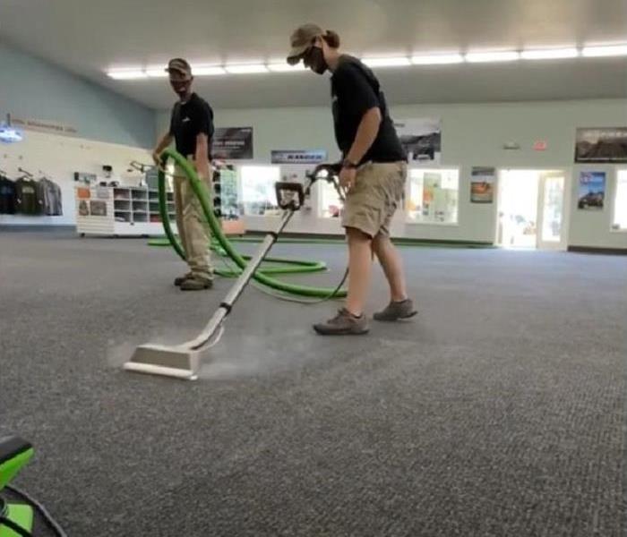 Technician using a hot water extraction tool to deep clean office carpets.