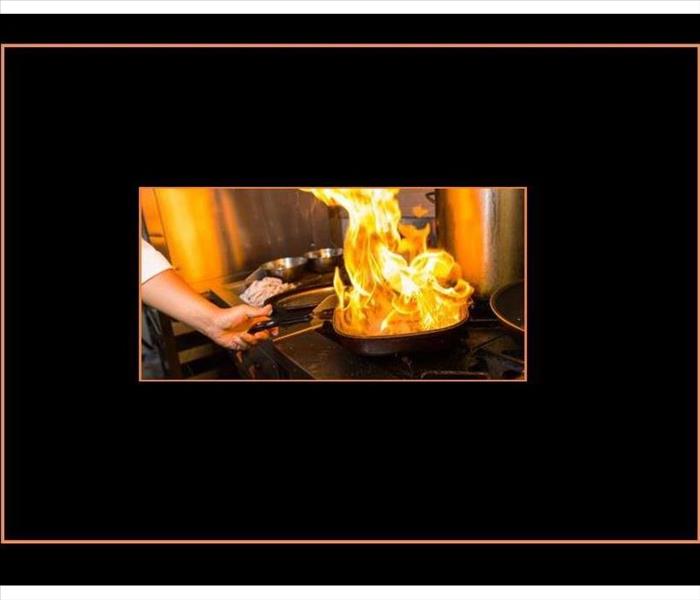 large flames rising from a pan on a range, black background with orange frame